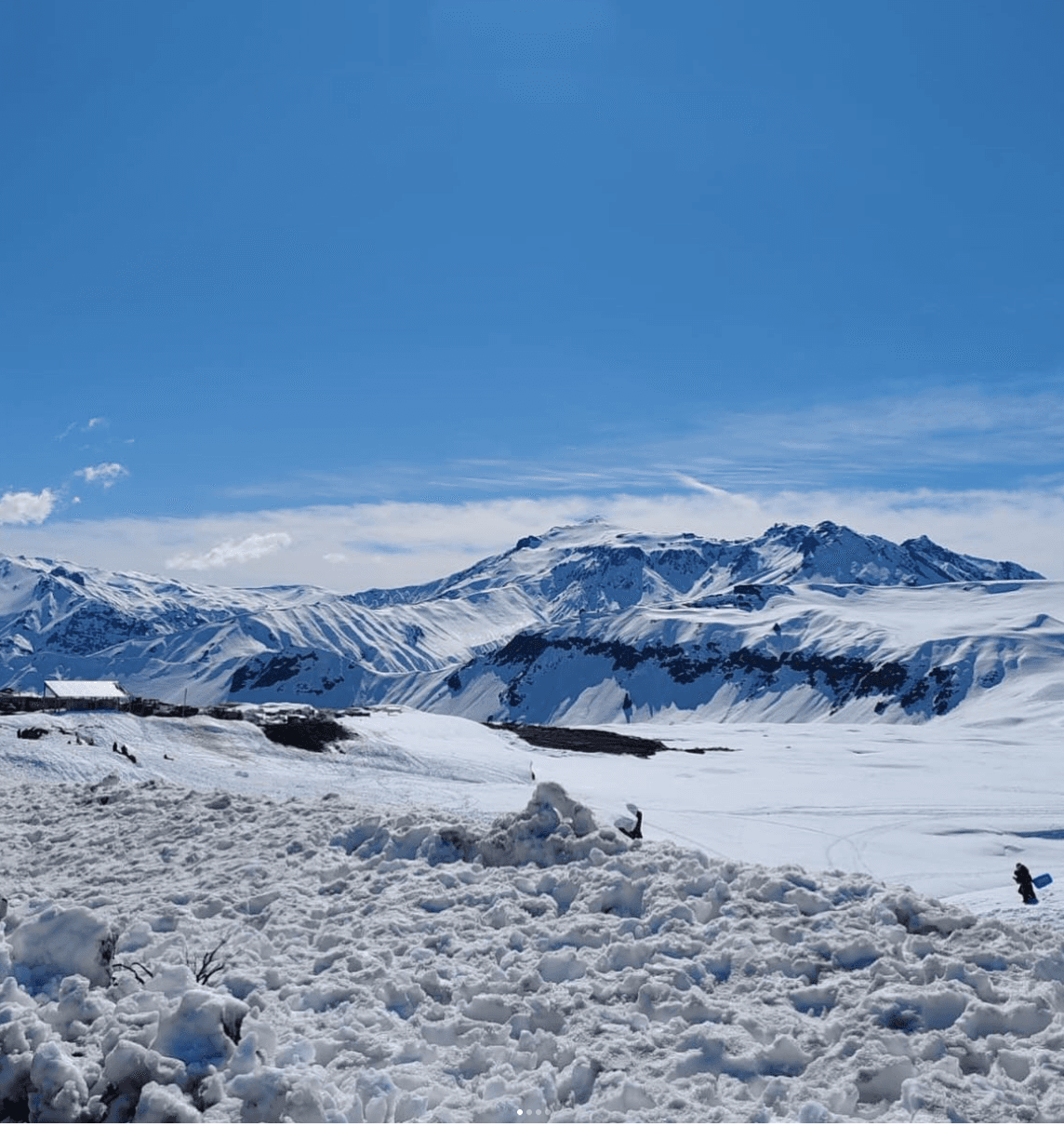 Cordillera de los Andes cubierta de nieve en un día despejado, con visitantes jugando en la nieve