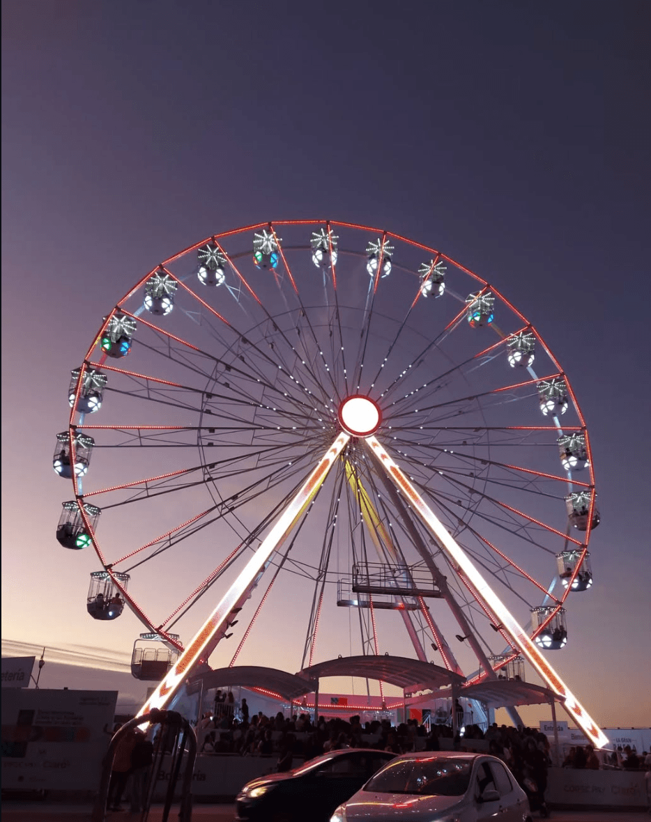 Rueda de la fortuna iluminada de noche con góndolas de colores contra el cielo del atardecer